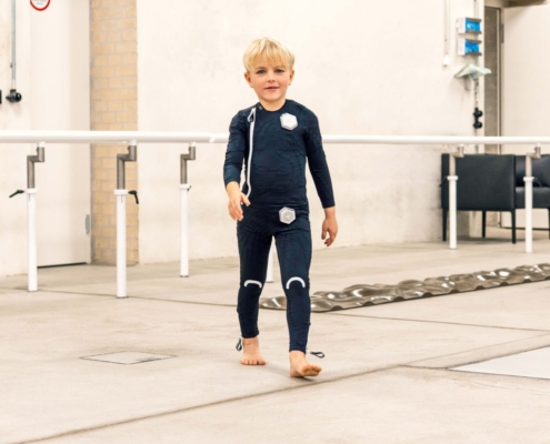 Kleiner Junge mit neurologischer Erkrankung läuft im Exopulse Suit kids bei Münch & Hahn Sanitätshaus