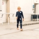 Kleiner Junge mit neurologischer Erkrankung läuft im Exopulse Suit kids bei Münch & Hahn Sanitätshaus